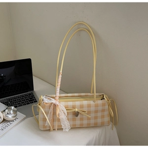 Detail of yellow plaid shoulder bag with floral lace bow and silver heart pendant