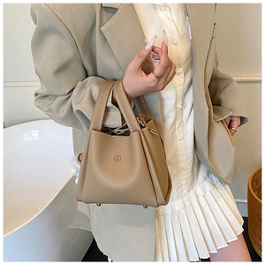 Close-up of khaki pebbled leather bucket bag with double handles and embossed logo