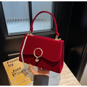 Macro detail of red velvet handbag with pearl chain and golden ring buckle