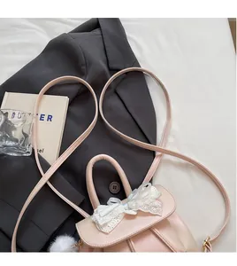 Detail of light pink mini backpack featuring delicate white lace bow and leather strap