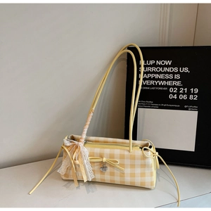Detail of yellow gingham shoulder bag featuring white lace ribbons and heart pendant