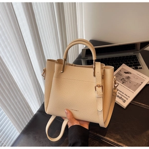 Close-up of beige lychee grain leather bucket bag with gold hardware and logo
