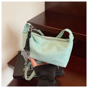 Detail of light green suede shoulder bag with heart charm on wooden steps