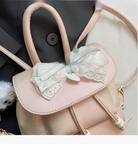 Detailed view of pink leather backpack with large lace bow and heart pendant