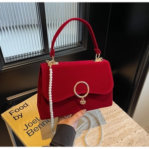 Detail of red velvet handbag with gold round buckle and detachable white pearl strap