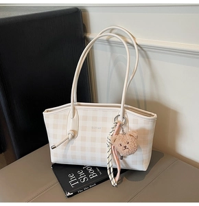 Detailed macro view of checkerboard tote bag with chic text and cute bear charm decoration