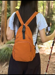 Detail of orange nylon crossbody bag with dual zippers and elastic drawstrings
