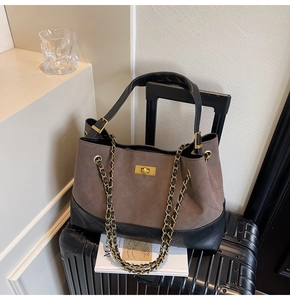 Detailed close-up of quilted tote bag with gold clasp and chain strap on a suitcase