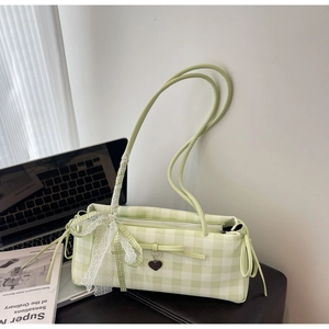 Detailed close-up of green checkered underarm bag with lace bow and heart metal pendant