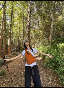 Outdoor lifestyle shot of a multi-functional orange nylon crossbody bag with hiking gear