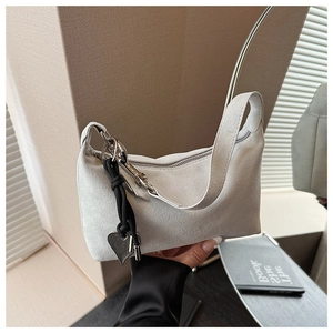 Detail of cream suede crescent shoulder bag with silver chain and heart charm