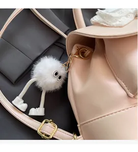 Macro detail of white plush monster keychain with sneakers on pink lace leather backpack