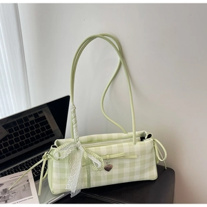 Detail of light green checkered underarm bag featuring lace bow and metal heart pendant