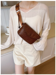 Détail du sac bandoulière tressé marron foncé avec pendentif cœur et large sangle