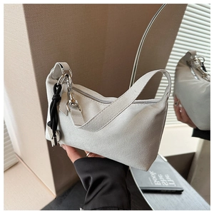 Detail showing the white suede texture and black braided tassel on this shoulder bag