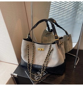 Detail of quilted bucket bag with gold clasp and chain strap on a dark surface