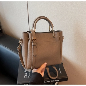Close-up of pebble leather texture on a tan bucket bag with polished metal hardware