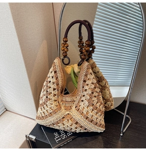 Detailed view of woven straw tote bag with brown wooden bead accents and wavy texture