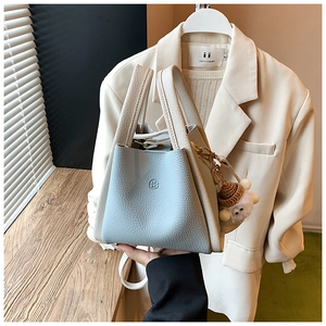 Detail of blue and beige bucket bag featuring a textured finish and cute bear charm