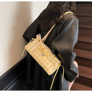Detail of yellow checkered shoulder bag with lace edges and bow decoration