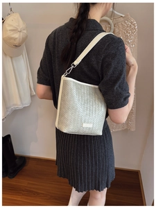 Détail de la texture tressée gris clair du sac seau avec bordures en cuir blanc