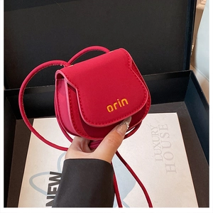 Macro shot of rose red suede mini saddle bag with yellow orin logo in luxury gift box