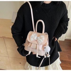 Detail of small peach bow backpack with plush monster charm and wood bead drawstring