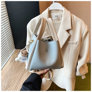 Detail of light blue lychee leather bucket bag with UM logo and plush sheep charm