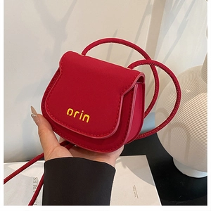 Close-up of a mini red saddle bag with matte finish and orin logo on textured background