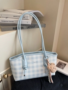 Blue and white checkered tote bag with a brown teddy bear charm and knotted shoulder strap