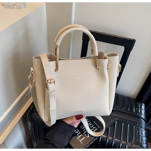 Detail of light beige lychee leather bucket bag with gold hardware and top handle