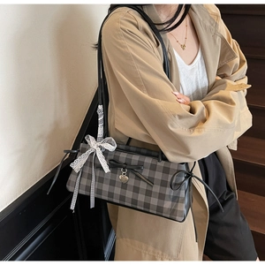 Detailed shot of gingham shoulder bag with black bow, heart charm and lace ribbon trim
