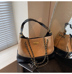Detail of quilted tote bag featuring metal chain strap and turn-lock closure