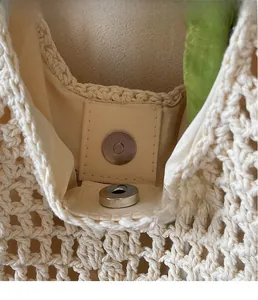 Macro shot of silver magnetic metal clasp and texture on off-white woven tote bag