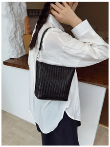Détail du sac seau noir tissé avec bandoulière en cuir et finitions métalliques