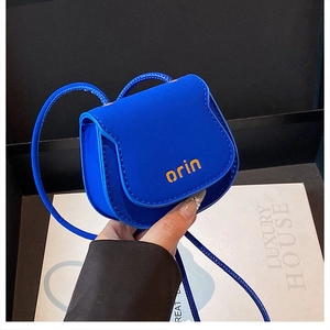 Detail shot of mini electric blue crossbody bag with orange logo and cord strap