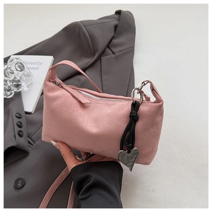 Detail of pink suede rectangular shoulder bag with silver zipper and heart charm decoration