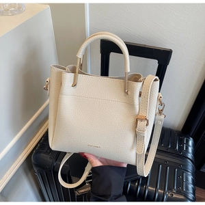 Detailed close-up of cream-colored pebble leather bucket bag with gold-tone hardware accents