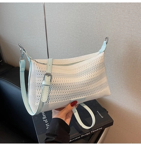 Dettaglio della borsa intrecciata bianca con tracolla in pelle azzurra e fibbia argento