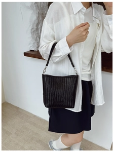 Gros plan sur la texture en cuir tressé noir et les boucles en métal de ce sac seau
