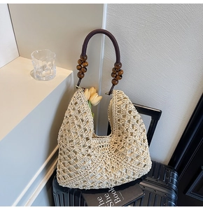 Detail of woven straw tote bag with elegant wooden bead handles and hollow crochet pattern