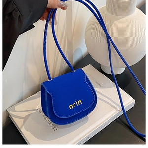 Detail view of mini Klein blue leather crossbody bag with yellow orin lettering