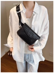 Détail d'un sac bandoulière noir tissé porté par un mannequin avec large sangle réglable