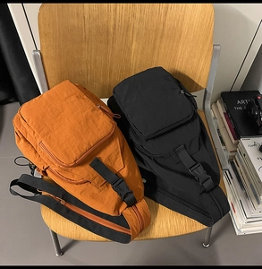 Detailed view of nylon sling bags in orange and black with functional zipper compartments