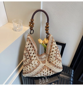 Close-up of woven straw tote bag with intricate diamond patterns and wooden bead handle