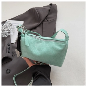 Close-up of mint green suede handbag with silver metal ring and zipper details