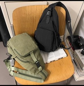 Detail of black and olive green nylon crossbody bags with multi-pocket design on a wooden chair