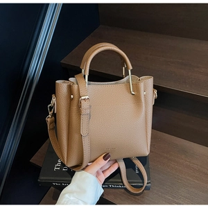 Detail of brown litchi pattern leather bucket bag on books with champagne gold hardware