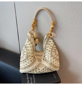 Detail of woven straw tote bag with large wooden beads on handle and tulip accessory
