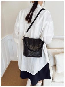 Détail d'un sac seau tissé noir avec bandoulière amovible dans un décor moderne